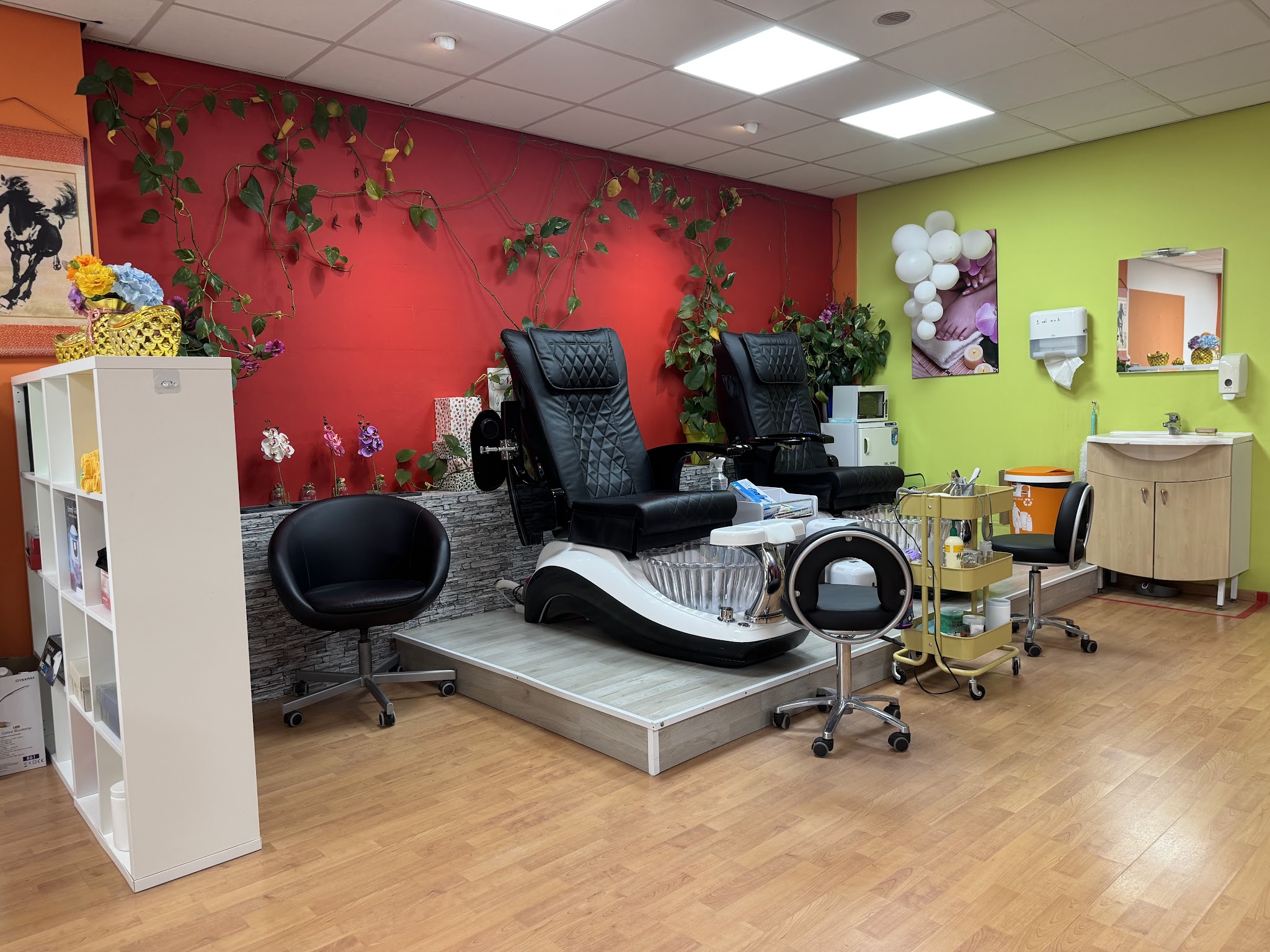 De salon van HS Nail Studio: een rode muur met klimop, een limoengroene muur en zwarte pedicurestoelen