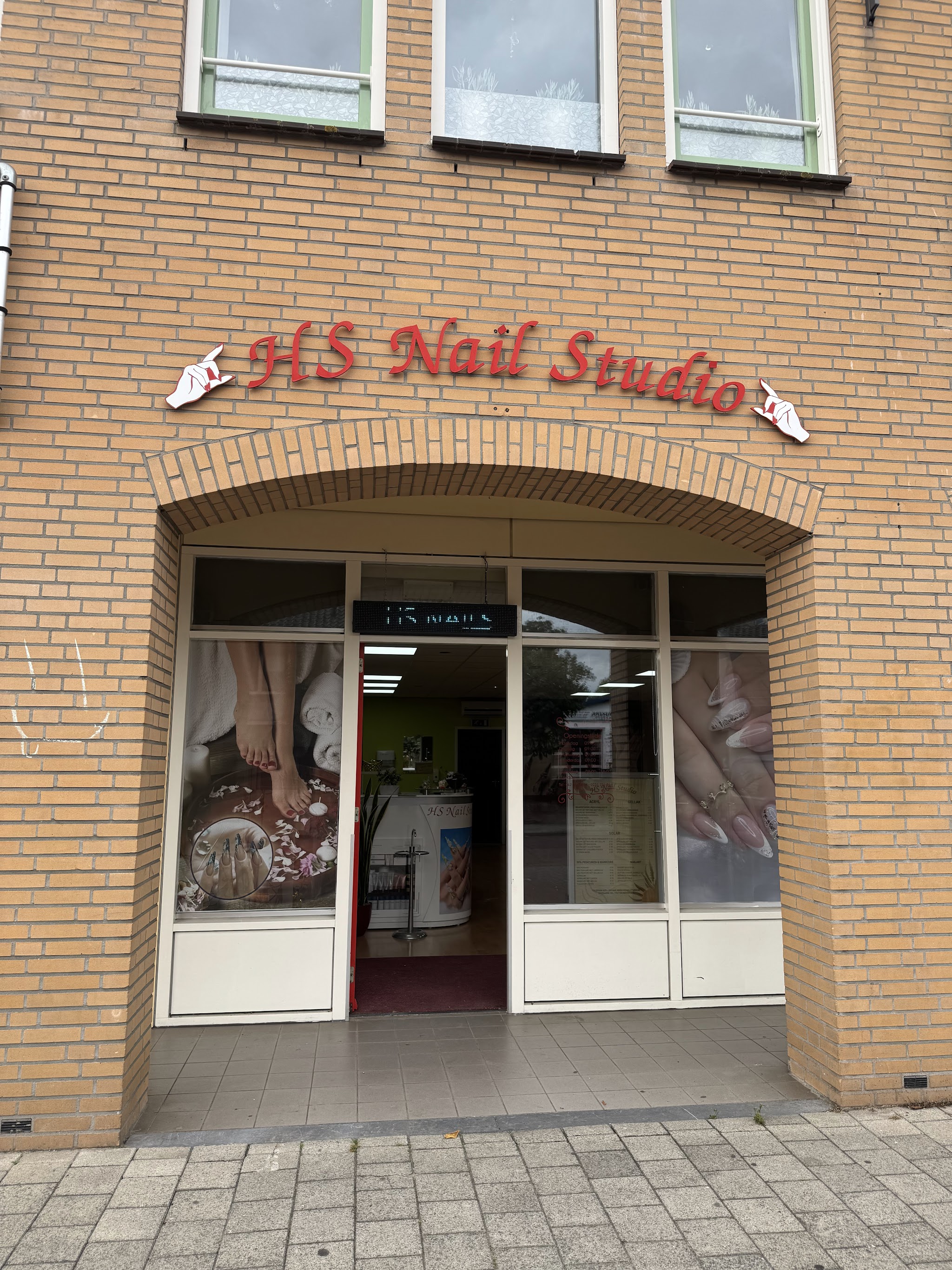 De gevel van HS Nail Studio met de rode letters HS Nail Studio boven de bakstenen boog