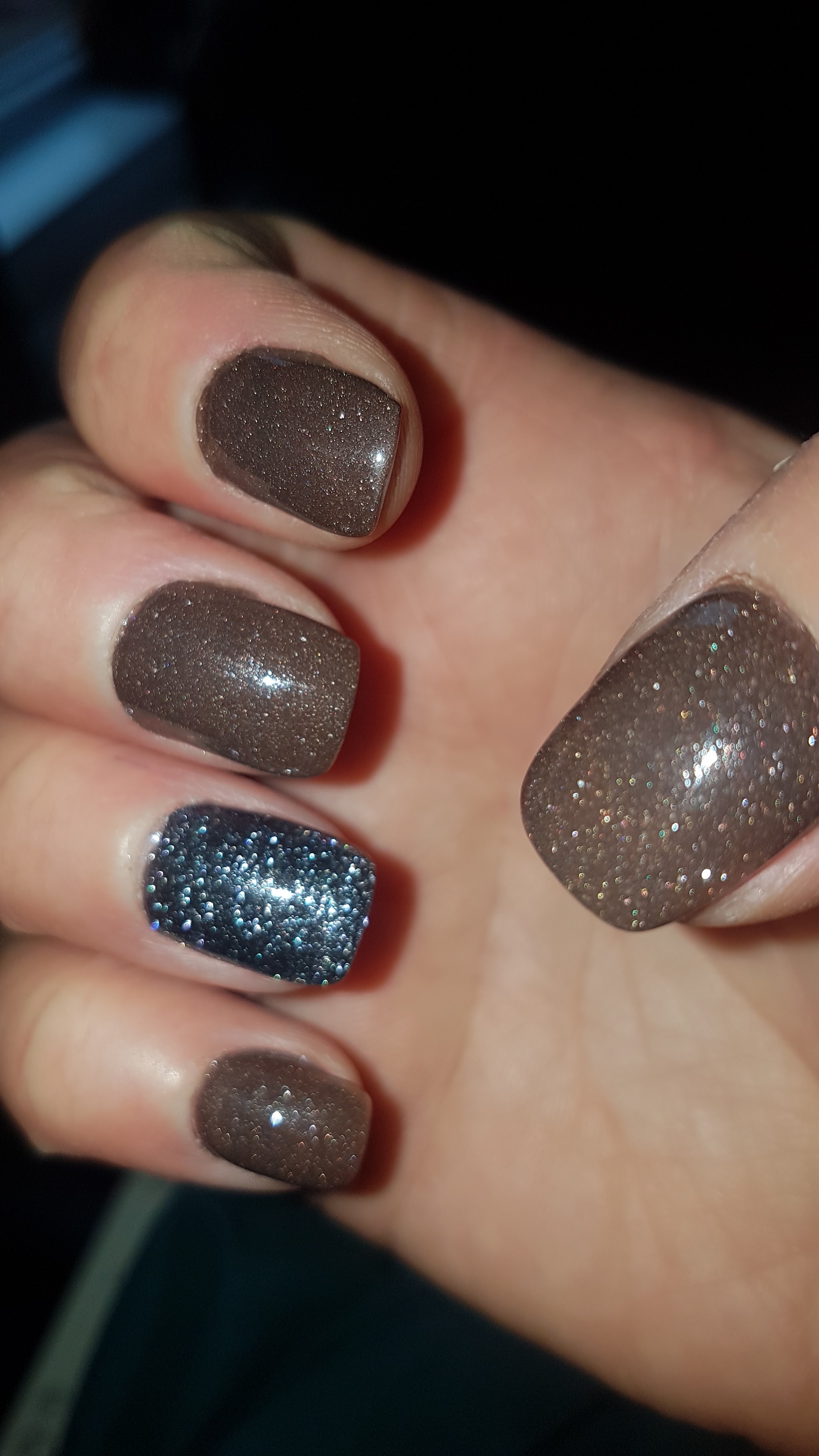 Korte nagels met bruine glitter en een blauwe glitternagel